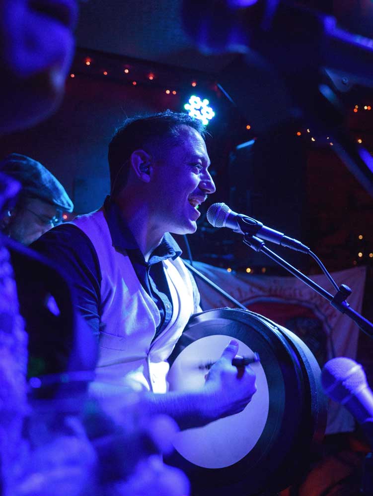 Peter playing the bodhran while singing at a gig